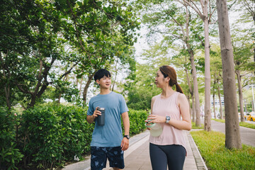 young Asian couple staying hydrated after running jogging. Healthy lifestyle concept.