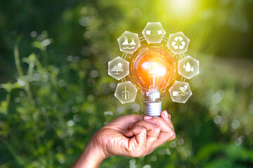 in hand light bulb on green nature background green energy icon around. Investing in environmental,...