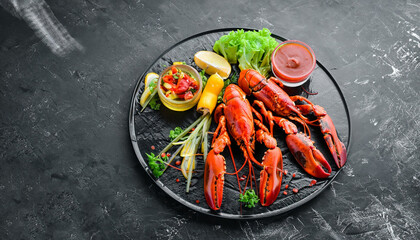 Boiled lobster with vegetables on a black stone plate. Seafood. Top view. Free space for your text.