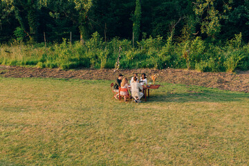 high view of family or friends having dinner outdoors in park sitting on table