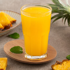 Fresh delicious pineapple juice smoothie in glass cup on gray table background.