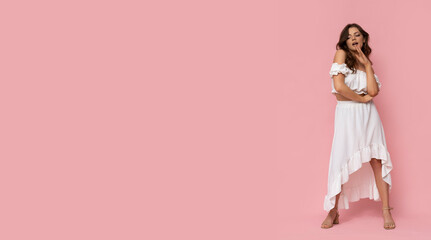 Very attractive young woman in white dress on isolated pink background.