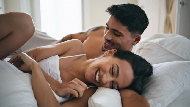 Laughing newlyweds having fun bed close up. Smiling man kissing shoulder of lady