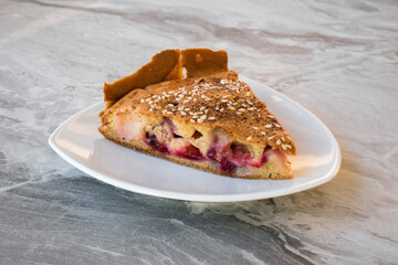 A slice of homemade pie with cherries and plums sprinkled with sesame seeds