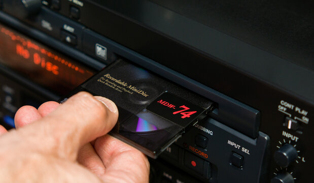 Man's hand removes a disc from the slot of a professional mini disc player