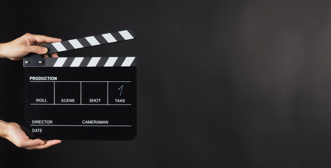 Hand is holding Black clap board or movie slate  use in video production , movie ,film, cinema industry on black background.It have write in number. - obrazy, fototapety, plakaty