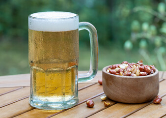 Glass mug of beer and bowl of nuts