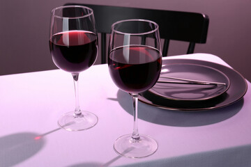 Romantic table setting with glasses of red wine indoors