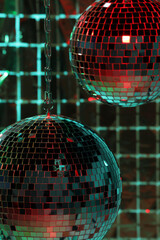 Shiny disco balls against foil party curtain under color lights