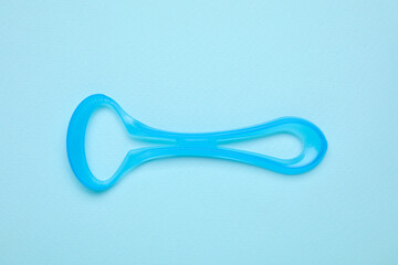 Tongue cleaner on light blue background, top view