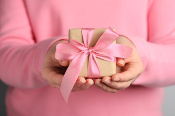 Woman holding gift box with pink bow, closeup