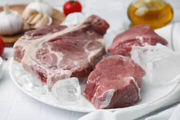 Fresh raw cut beef and ice cubes on white table, closeup