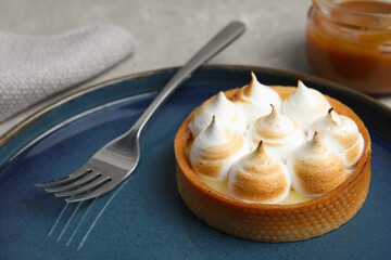 Tartlet with meringue on grey table, closeup. Delicious dessert