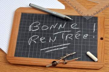 Bonne rentrée écrit sur une ardoise d'école avec du matériel scolaire