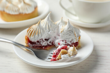 Tartlet with meringue served on white wooden table, closeup. Delicious dessert