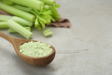Natural celery powder in wooden spoon on grey table, closeup. Space for text