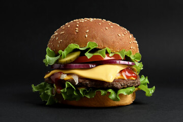 Delicious burger with beef patty and lettuce on black background
