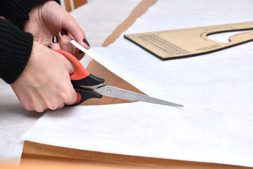 woman cutting a white cloth with scissors - obrazy, fototapety, plakaty