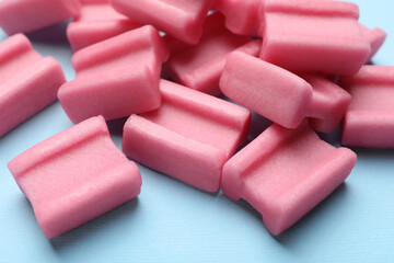 Tasty pink chewing gums on light blue background, closeup