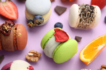 Delicious macarons, orange and berries on violet table, closeup