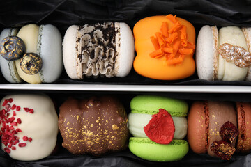 Cardboard box with delicious macarons as background, top view