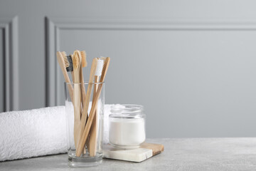 Fototapeta na wymiar Bamboo toothbrushes, towel and jar of baking soda on light grey table, space for text