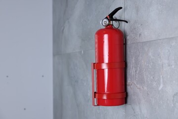 Obraz premium Fire extinguisher on grey wall, space for text