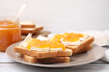 Fototapeta na wymiar Tasty sandwiches with brie cheese and apricot jam on white wooden table, closeup
