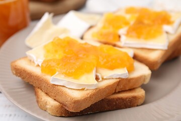 Tasty sandwiches with brie cheese and apricot jam on plate, closeup