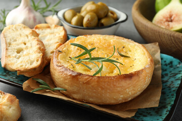 Tasty baked brie cheese and products on grey table