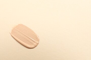 Smear of skin foundation on beige background, top view. Space for text