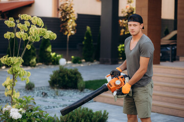 Worker on a street in autumn with a leaf blower