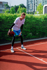 Obraz premium a Tall guy basketball player with the ball shows his dribbling skills during practice on the basketball court in the park 