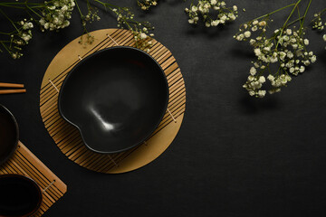 Empty black slate plate and dried flowers on black stone table for menu, recipe and restaurant dish
