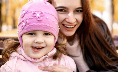 Obraz premium Happy family mom and little girl playing outdoors in autumn park. Little girl and her mother in the autumn park. soft focus