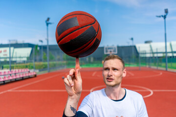 Fototapeta premium Close-up of a guy basketball player spinning a basketball on his finger showing his basketball freestyle skills 