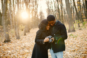 Black couple walking in park and looking in camera in their hands