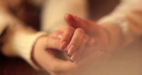 Close-up of the hands of a couple in love sitting at a table in a cafe on a romantic date. Male and female hands interacting with each other at the moment of a romantic meeting of a couple in love.