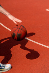Close-up of a basketball guy's shadow on the floor of a basketball court while dribbling the ball