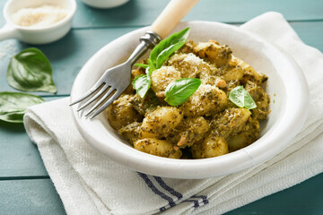 Potato gnocchi. Traditional homemade potato gnocchi with sauce pesto, kitchen table and basil on old rustic turquoise kitchen table. Traditional Italian food. Traditional Italian food. Top view.
