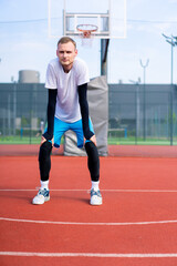 Fototapeta premium A Tall guy basketball player actively warming up on an outdoor basketball court before practice starts