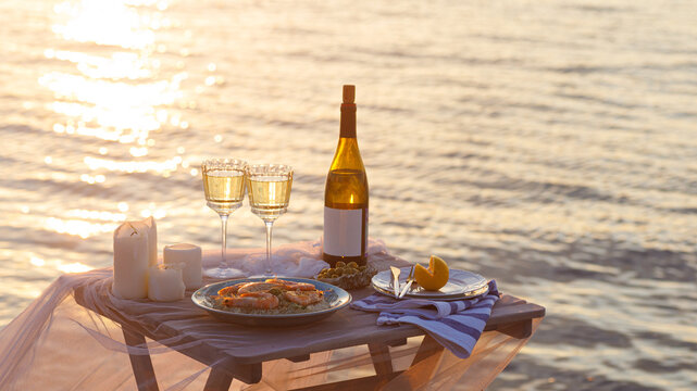 Romantic Sunset Dinner On The Beach. Table Honeymoon Set For Two With Luxurious Food, Glasses Of Champagne Drinks In A Restaurant With Sea View. Summer Love, Romance Date On Vacation Concept.