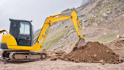 Excavator works in the highlands. Makes a trench for communications. water and electricity. in the gorge of the mountains. repair and expansion of a road