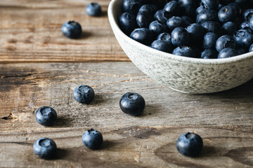 Bowl with blueberries on a wooden background, close up.