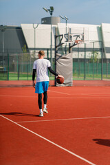 a Tall guy basketball player with the ball shows his dribbling skills during practice on the basketball court in the park 