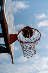 A close-up of a basketball hoop into which a basketball hits the concept of admiration for the game of basketball and love of working out 