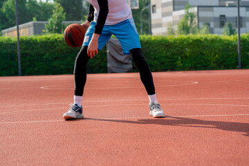 a Tall guy basketball player with the ball shows his dribbling skills during practice on the basketball court in the park 
