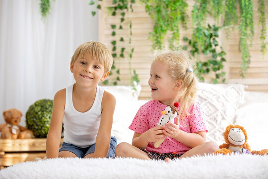 Cute sweet toddler children, tickling feet on the bed, laughing and smiling, childish mischief, happiness