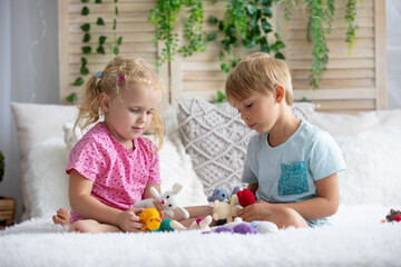 Cute sweet toddler children, tickling feet on the bed, laughing and smiling, childish mischief,...