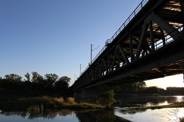 Fototapeta na wymiar A bridge over water with trees and blue sky